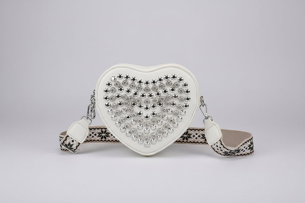 Heart-shaped handbag with rhinestone embellishments held by a person.